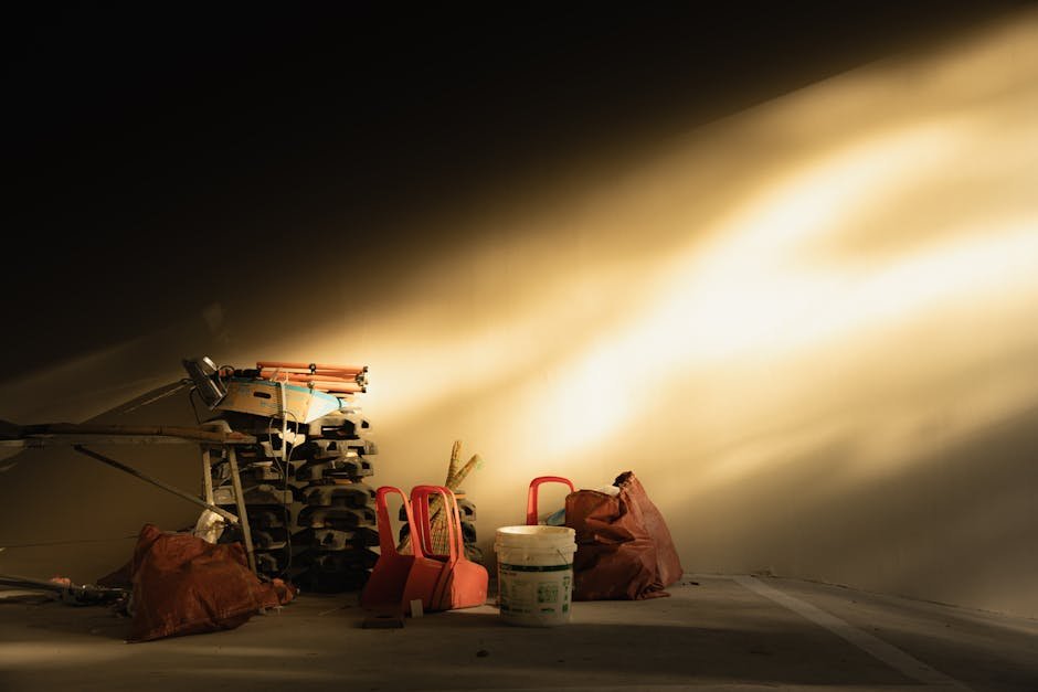 Warm sunlight illuminates scattered construction tools and red chairs in a garage corner.